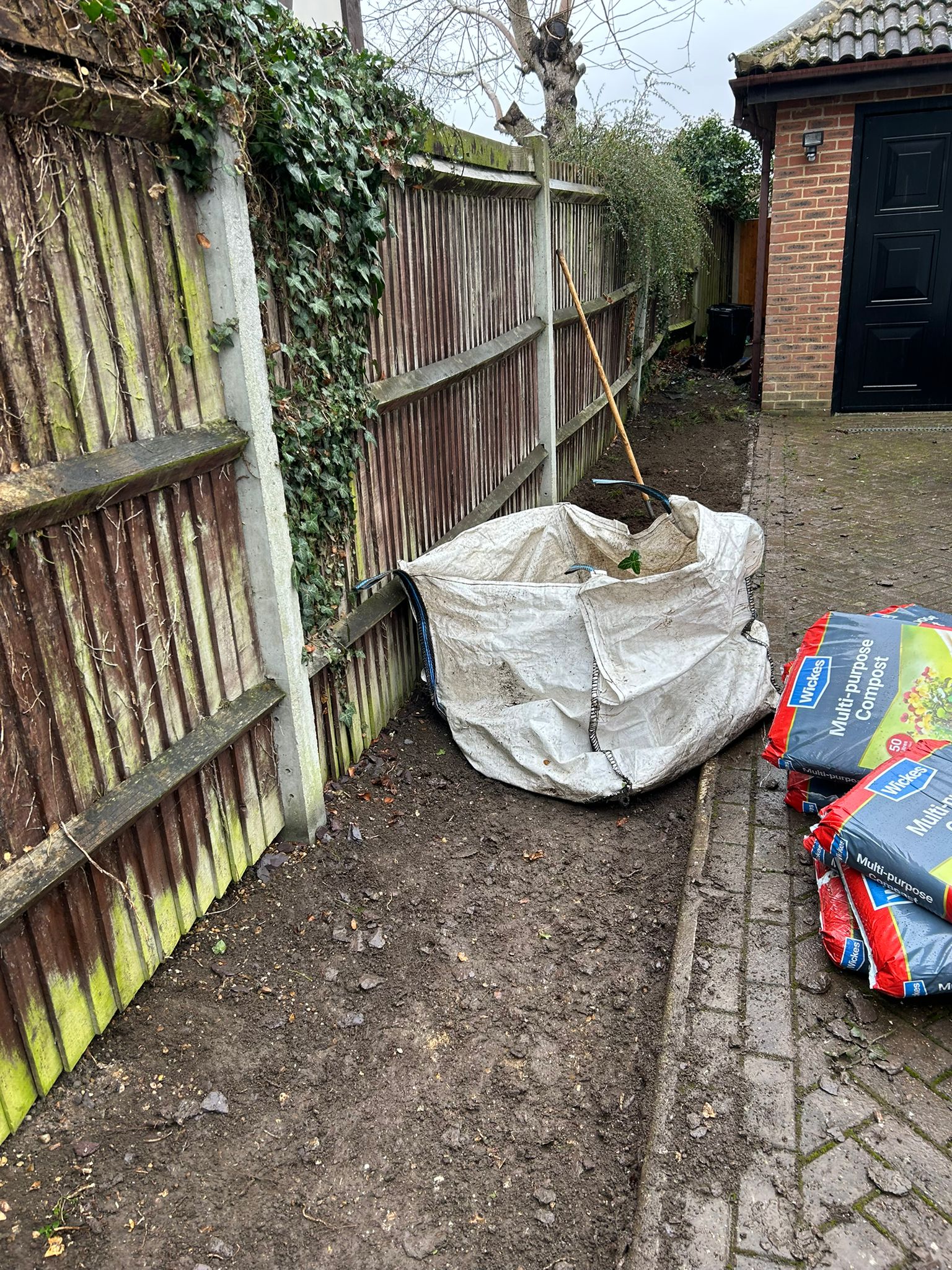 Narrow driveway planting border cleared and prepared for new shrubs