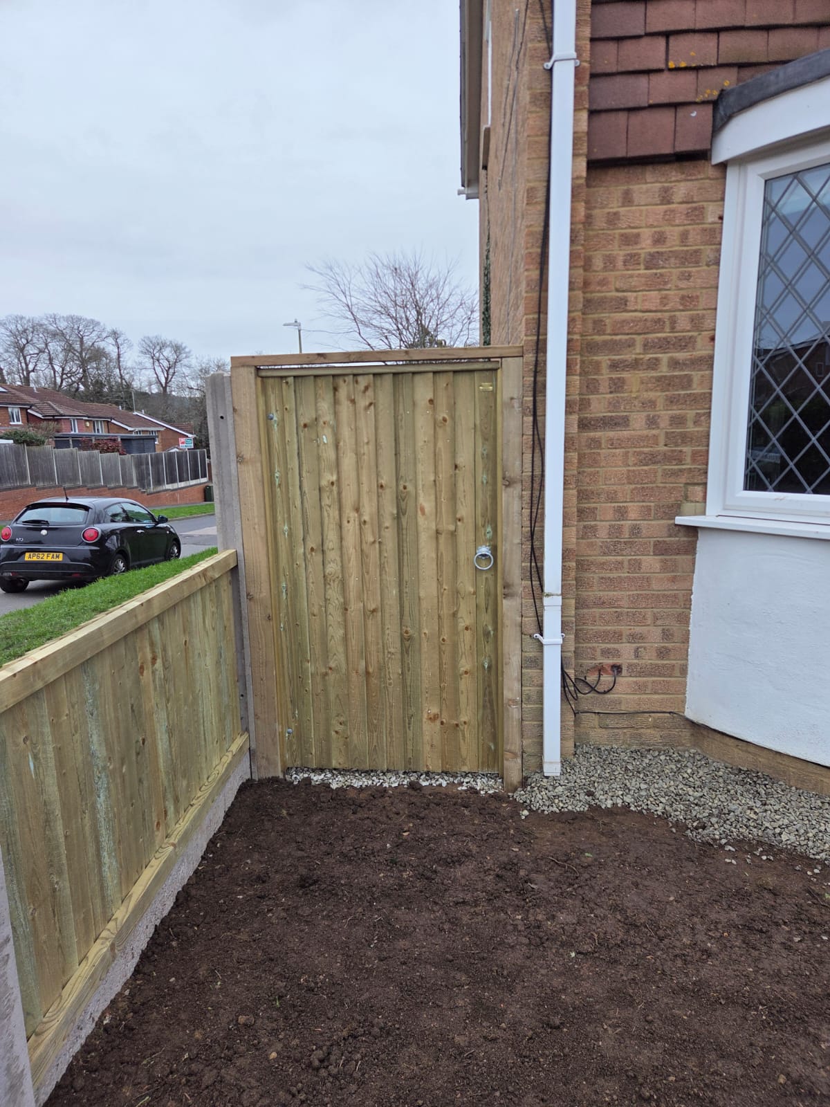 New timber side gate enclosing a small garden area beside a house